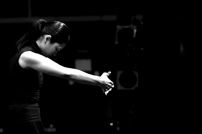 A woman in a black sleeveless top with arms outstretched